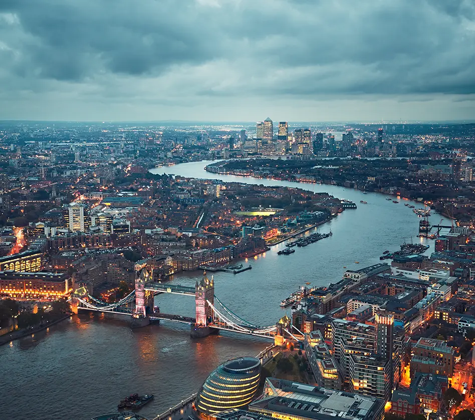 Aerial view of London with Tower Bridge and River Thames at dusk.