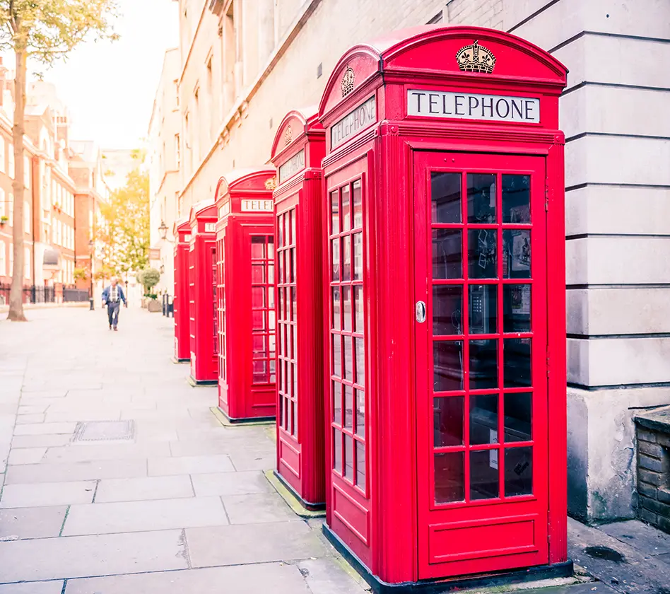 Red phone booths line a sunny London street.